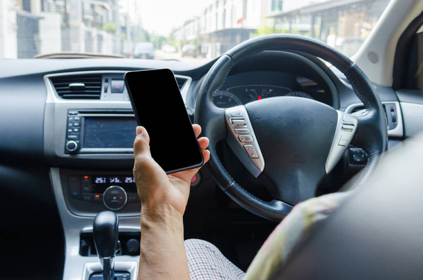 Damska ręka trzymająca telefon komórkowy w samochodzie Korzystanie ze smartfona komórkowego w samochodzie. - Zdjęcie, obraz