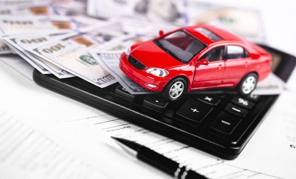 piros autó, számológép, toll dollárral bankjegyek közelkép a papír formában - Fotó, kép