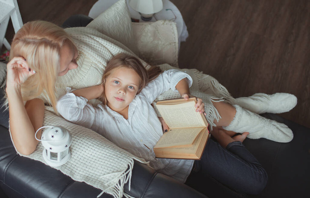 The family in the period of self-isolation reads books at home on the couch. How to keep yourself busy during quarantine without leaving your home - Foto, Bild