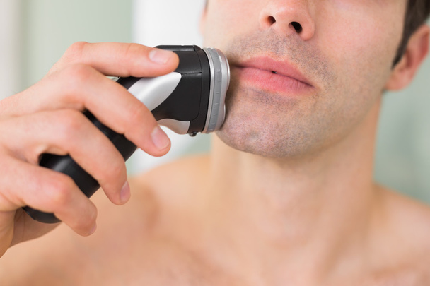 Extreme Close up of shirtless man shaving with electric razor - Photo, Image
