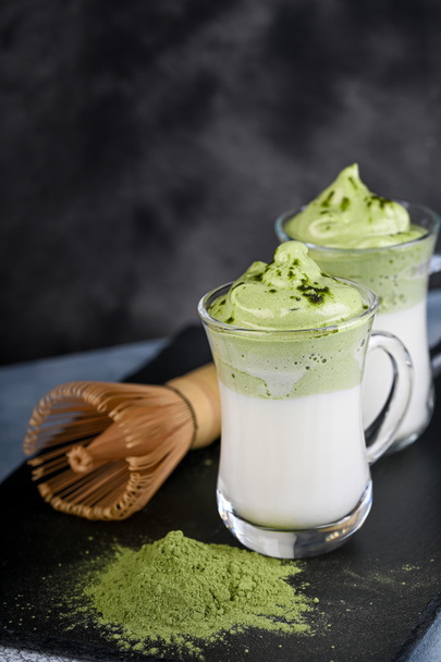 Zwei Tassen Dalgona Matcha Latte, ein cremiger Matcha mit Schlagsahne, auf dunklem Hintergrund. Matcha grüner Tee. - Foto, Bild