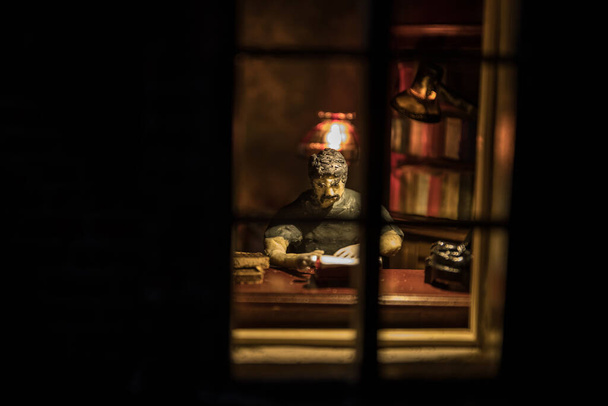 Realistyczny salon z meblami i oknem w nocy. Mężczyzna siedzący na stole w ciemnym pokoju. Koncepcja pozostania w domu podczas globalnej pandemii wirusowej. Skupienie selektywne. - Zdjęcie, obraz