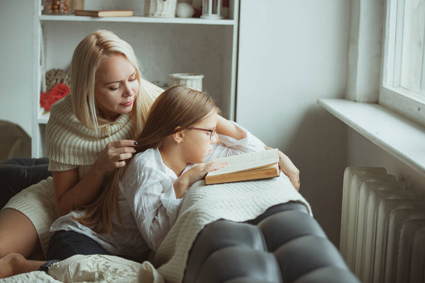 The family in the period of self-isolation reads books at home on the couch. How to keep yourself busy during quarantine without leaving your home - Foto, imagen