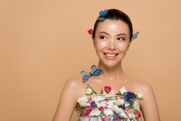 attractive smiling naked asian girl in flowers with butterflies on body isolated on beige - Φωτογραφία, εικόνα