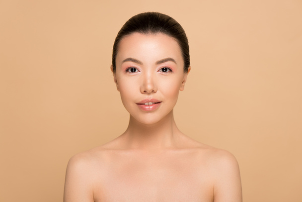 hermosa chica asiática desnuda con piel perfecta y maquillaje desnudo aislado en beige
 - Foto, Imagen