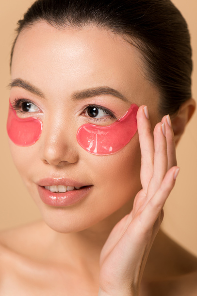 attrayant tendre asiatique femme avec rose collagène eye pads isolé sur beige
 - Photo, image