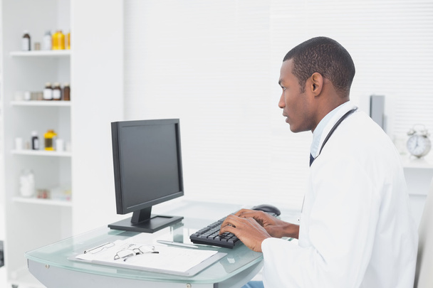 Concentrated doctor using computer at medical office - Foto, Bild