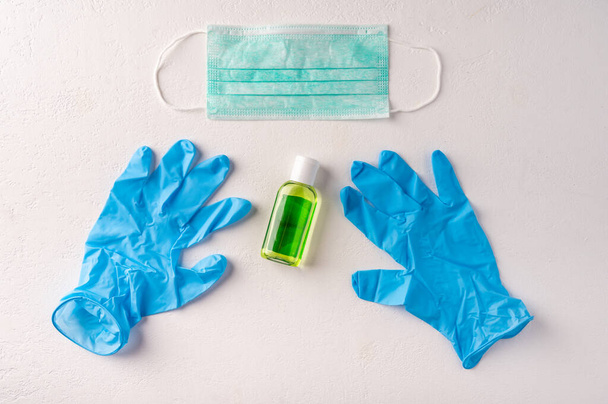 Hand sanitizer gel bottle, face mask, rubber gloves on light background. Copy space - Foto, Imagen