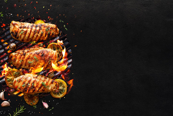 Grilled chicken breasts on a grill plate on black background with copy space, top view. Bbq background - 写真・画像