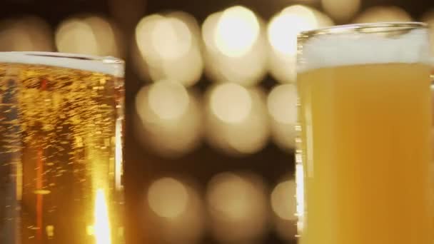 Δύο φίλοι τοστ κούπες μπύρα χυθεί μπύρα close-up bokeh φόντο - Πλάνα, βίντεο