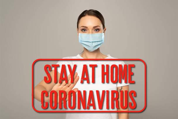 Mujer con máscara médica mostrando gesto de stop aislado en gris, estancia en casa e ilustración del coronavirus
   - Foto, imagen