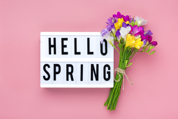 Virágcsokor frézia virágok, villásdoboz szöveggel Helló tavasz rózsaszín háttér Virágos nyaralás kártya Felülnézet Lapos fektetés Tavaszi koncepció. - Fotó, kép