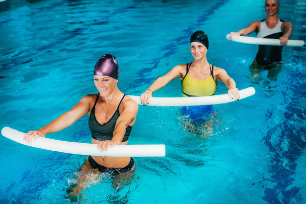 Aqua Aerobic Εκπαίδευση με Εξοπλισμός Water Fitness. Εκπαίδευση γυναικών με καλτσοδέτες κολύμβησης. - Φωτογραφία, εικόνα