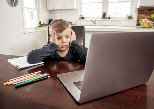 Coronavirus Outbreak. Lockdown and school closures. School boy with face mask watching online education classes feeling bored and depressed at home. COVID-19 pandemic forces children online learning. - Photo, Image
