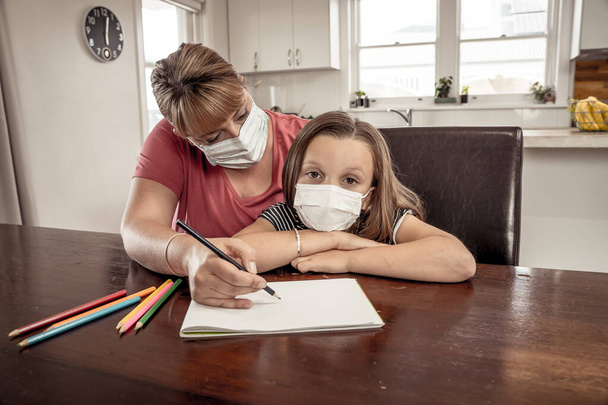 Coronavirus Outbreak. Lockdown and school closures. Mother helping bored daughter with face mask studying online classes at home. COVID-19 pandemic forces children and teachers online learning. - Valokuva, kuva