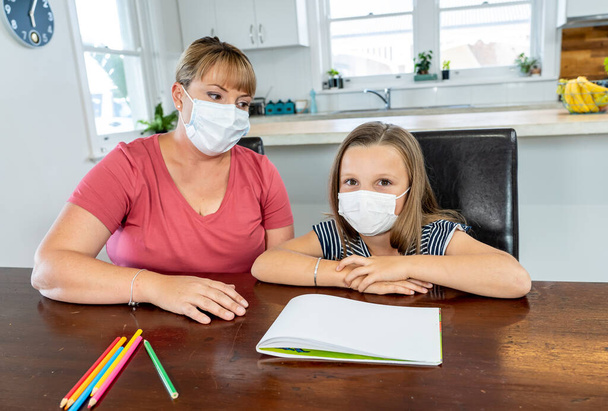 Coronavirus Outbreak. Lockdown and school closures. Mother helping bored daughter with face mask studying online classes at home. COVID-19 pandemic forces children and teachers online learning. - Photo, Image