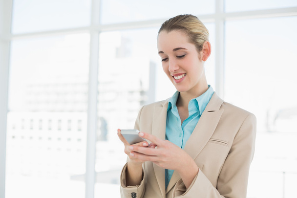 Content classy businesswoman texting with her smartphone - Fotó, kép