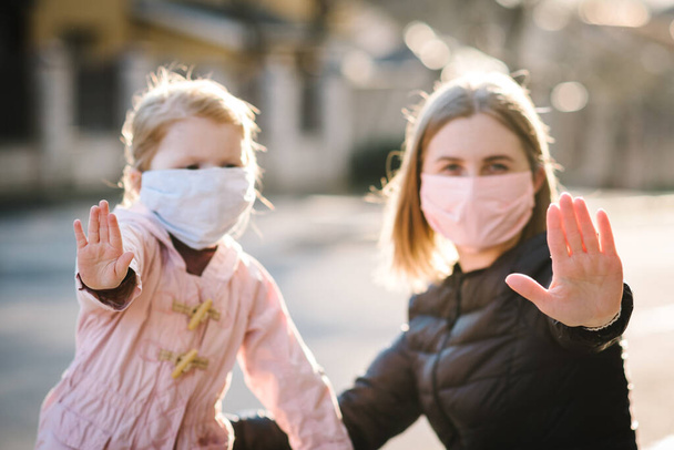 Stop the coronavirus and epidemic diseases. Healthy woman and child in medical protective mask showing gesture stop. Health protection and prevention during flu and infectious outbreak. - 写真・画像