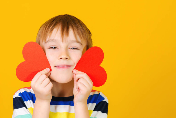 Cute child holding red hearts cards. Smiling boy with greetings card. Congratulations on Valentine's Day, Mother's Day, International Women's Day. Beautiful smile. Emotions. Love. - Foto, Imagem