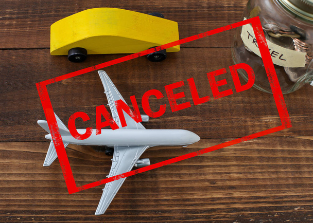 旅行ラベル付きの瓶の中の飛行機やコインと木製の車と画像上でキャンセル赤いテキスト - 写真・画像