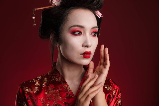 Image of attractive asian geisha woman in traditional japanese kimono isolated over red background - Fotoğraf, Görsel