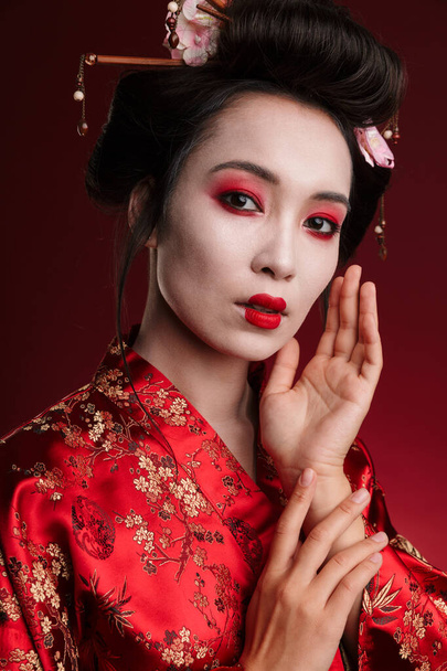 Image of attractive asian geisha woman in traditional japanese kimono isolated over red background - Foto, immagini