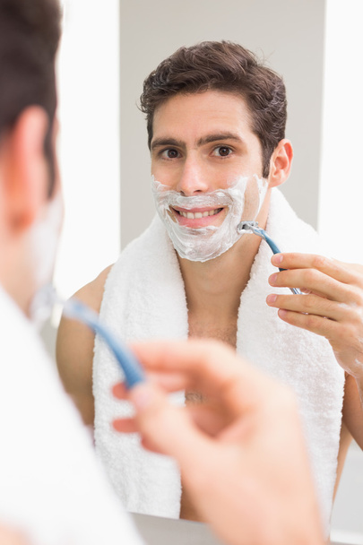 Handsome young man with reflection shaving in bathroom - Foto, Imagen
