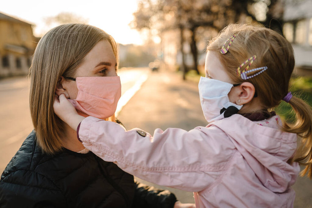Coronavirus the end concept. No more covid-19. Little girl, mother wear masks walk on street. Mom removes mask happy child. Family with kid outdoors. celebrating success. Pandemic is over, has ended. - Fotografie, Obrázek