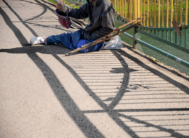 Бездомный просит милостыню на городской улице.
 - Фото, изображение