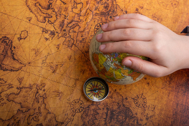 Compass on map beside a globe under hand - Photo, Image