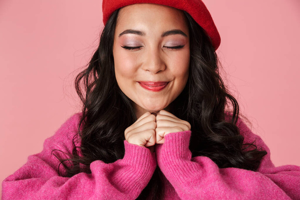 Image of young beautiful asian girl wearing beret smiling and clenching her fists at chest isolated over pink background - Fotografie, Obrázek