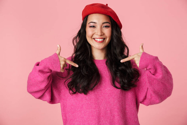 Image of young beautiful asian girl wearing beret laughing and pointing fingers at herself isolated over pink background - Zdjęcie, obraz