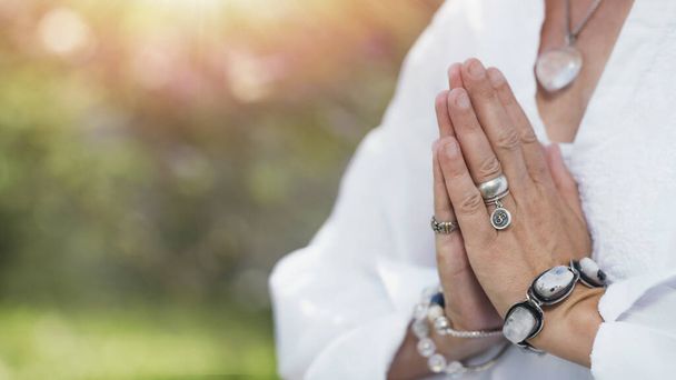 Imagem de perto de mãos femininas em posição de oração ao ar livre. Prática de autocuidado para o bem-estar
 - Foto, Imagem