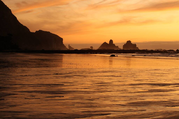 Puesta de sol en uno de los lugares más dramáticos de Nueva Zelanda, Motukiekie, en la costa oeste de la Isla Sur
. - Foto, imagen