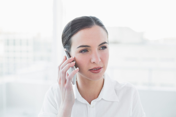Serious businesswoman using mobile phone in office - Foto, Imagem
