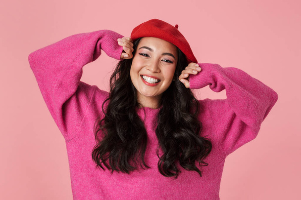 Image of joyful beautiful asian girl wearing beret rejoicing and smiling at camera isolated over pink background - Photo, Image