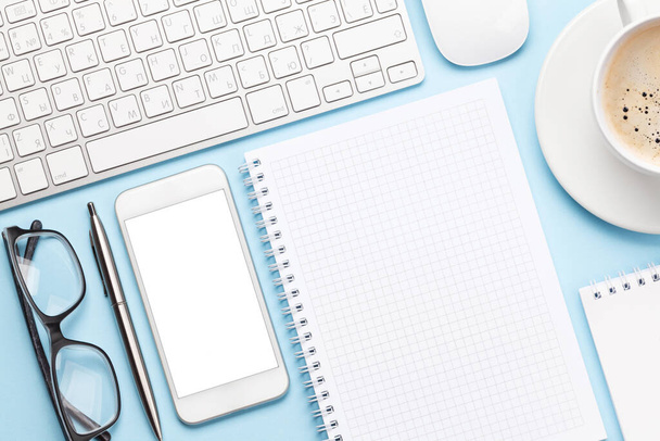 Blauer Arbeitstisch mit Computer, Smartphone, Zubehör und Kaffee. Draufsicht mit Platz für Text oder App. Flache Lage - Foto, Bild