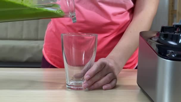 Frau gießt frischen grünen Smoothie aus dem Mixer ins Glas - Filmmaterial, Video