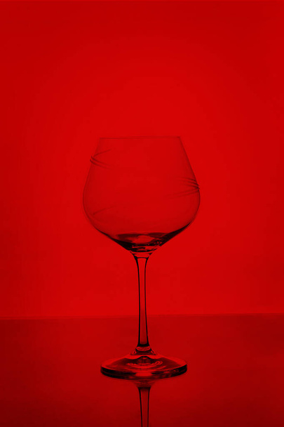 Vidrio de vino vacío claro aislado sobre fondo rojo
 - Foto, imagen