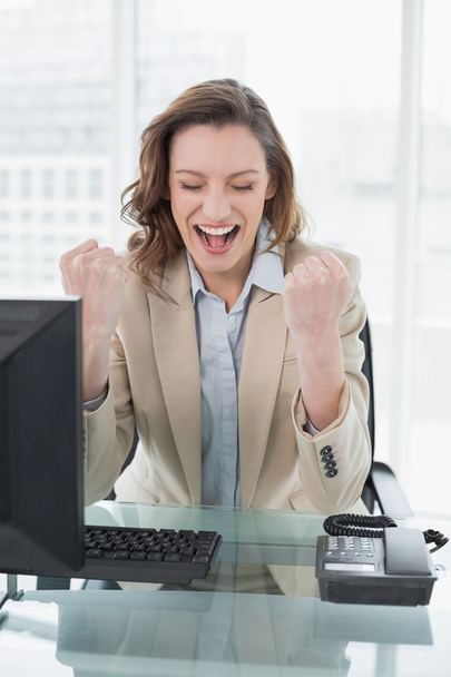 Businesswoman cheering with clenched fists in office - Foto, imagen