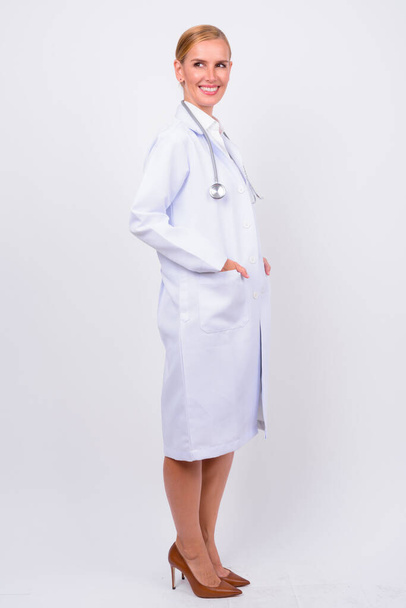 Studio shot van mooie blonde vrouw arts tegen witte achtergrond - Foto, afbeelding