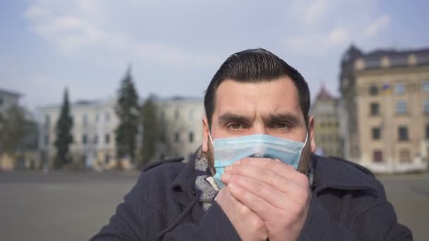 Elegante uomo caucasico barbuto tossisce in maschera medica sulla strada vuota della città. Squadra pandemica
 - Filmati, video