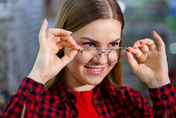La muchacha de la camisa saca y se mide las gafas
 - Foto, Imagen