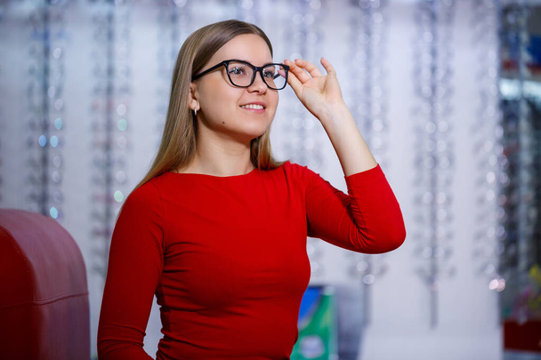 beautiful girl in an ophthalmology center picks up glasses for vision correction - Фото, изображение