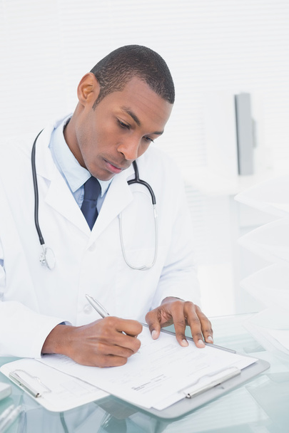 Serious male doctor writing a note - Foto, Imagen