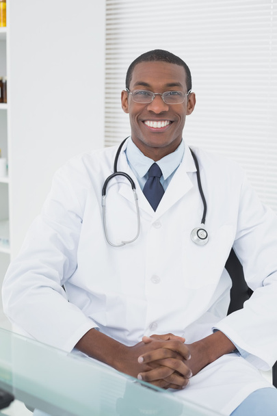 Smiling doctor with arms crossed in a medical office - Foto, Imagen