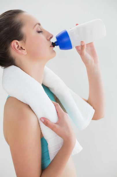 Fit woman with water bottle against wall - Foto, afbeelding