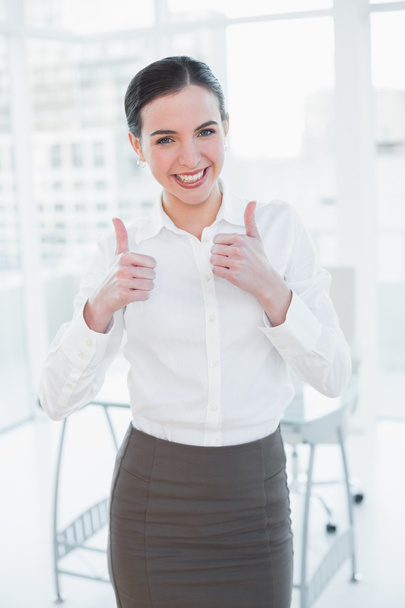 Elegant businesswoman gesturing thumbs up in office - Zdjęcie, obraz
