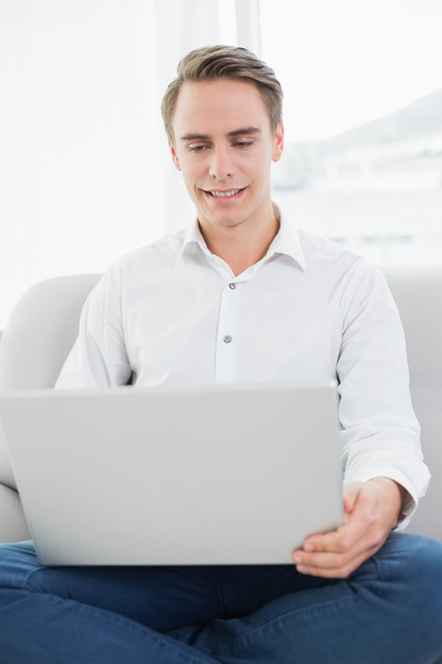Portrait of a casual young man using laptop on sofa - Photo, Image