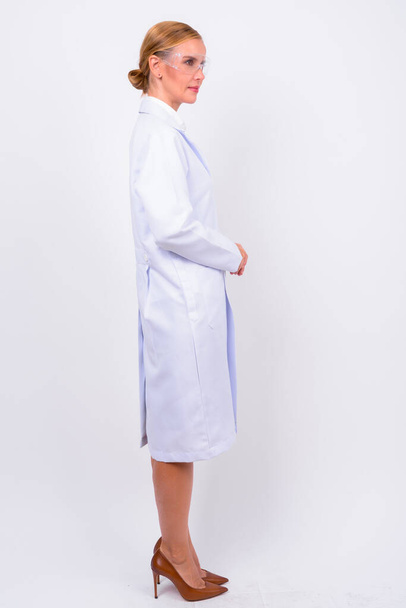 Studio shot of beautiful blonde woman doctor as scientist with protective glasses against white background - Photo, Image